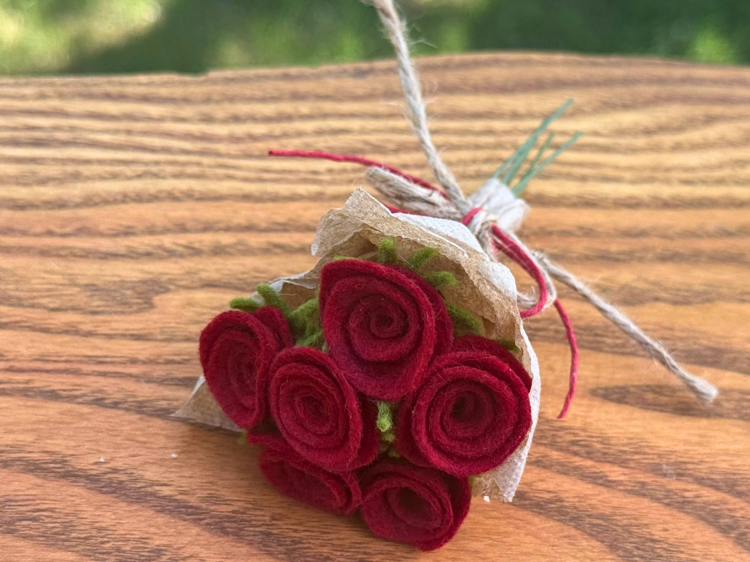 A red felt rose bouquet on a wood surface