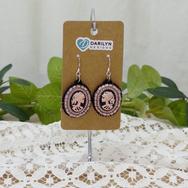 Pink and black beaded earrings featuring a skeleton cameo hanging from a stand.