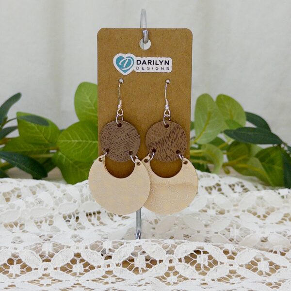 Walnut and silver-foiled birch geometric earrings hanging on a stand.