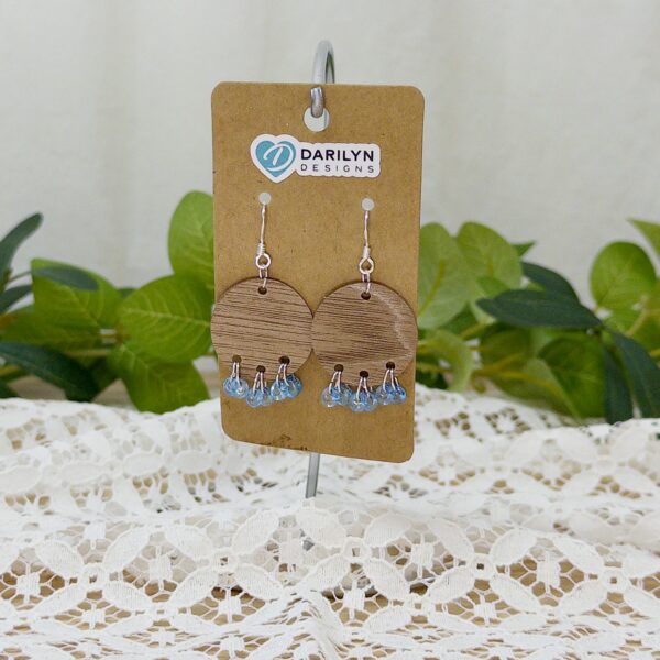 Round wood earrings with blue teardrop fringe.
