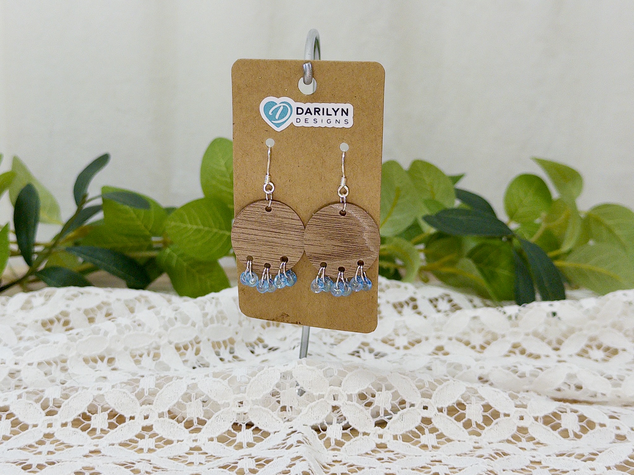 Round wood earrings with blue teardrop fringe.