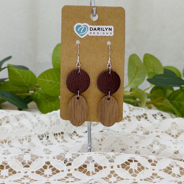 Faux leather and walnut geometric earrings hanging from a stand.