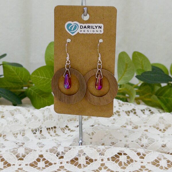 Walnut hoops with fiery red glass accents hanging from a stand.