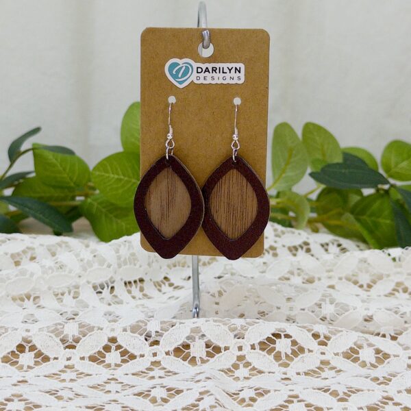 Faux leather and wood earrings hanging on a stand.