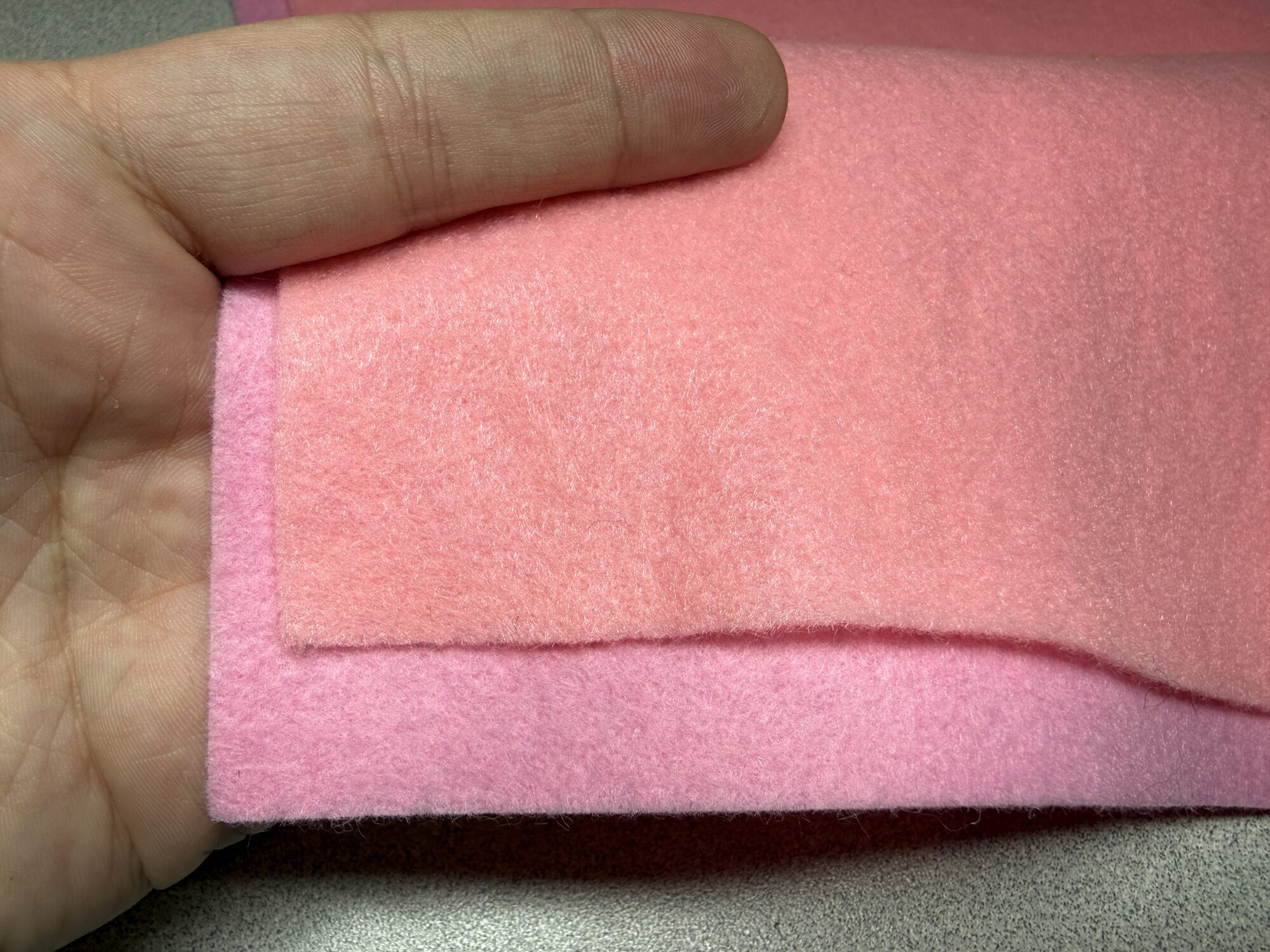 A sheet of acrylic felt layered on top of wool-blend felt on a work table