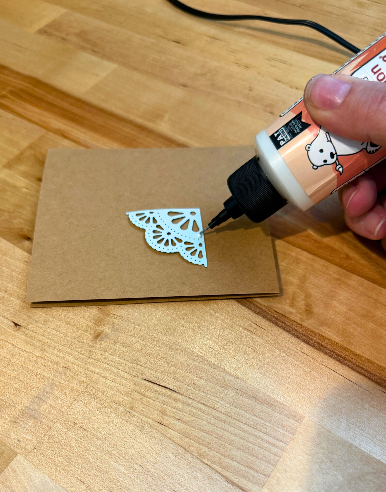 Applying a tiny dot of glue to a die-cut paper doily with the Bearly Art precision metal tip