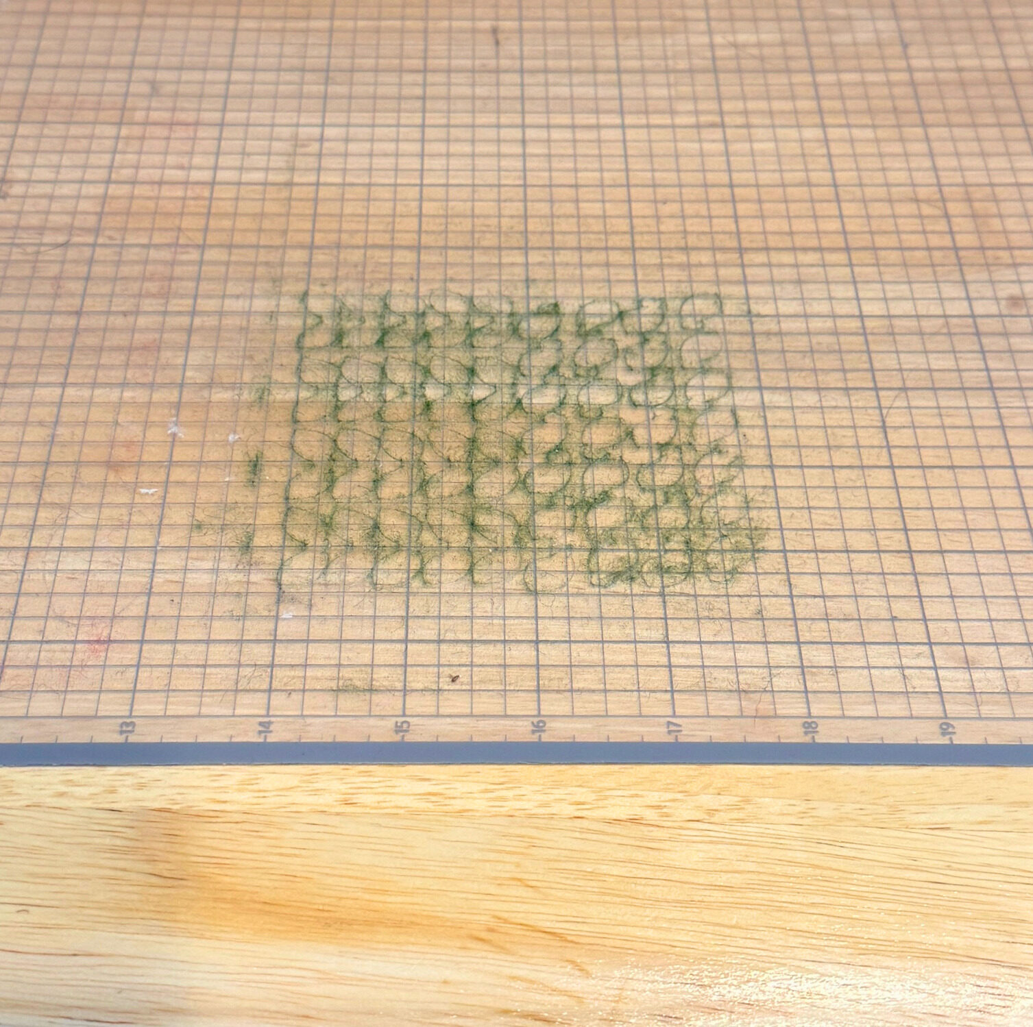 Green felt lint embedded in a cutting mat after cutting felt directly on the mat
