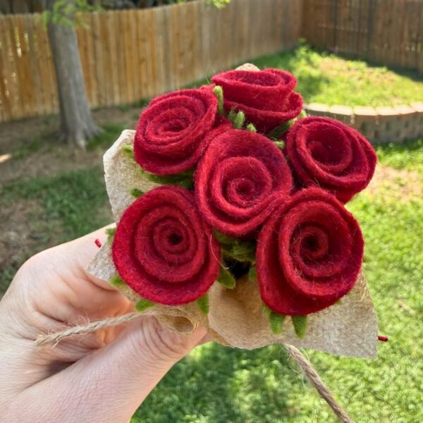 Six red felt roses seen from above, showing the rolled spiral of each flower and the green felt sepals underneath