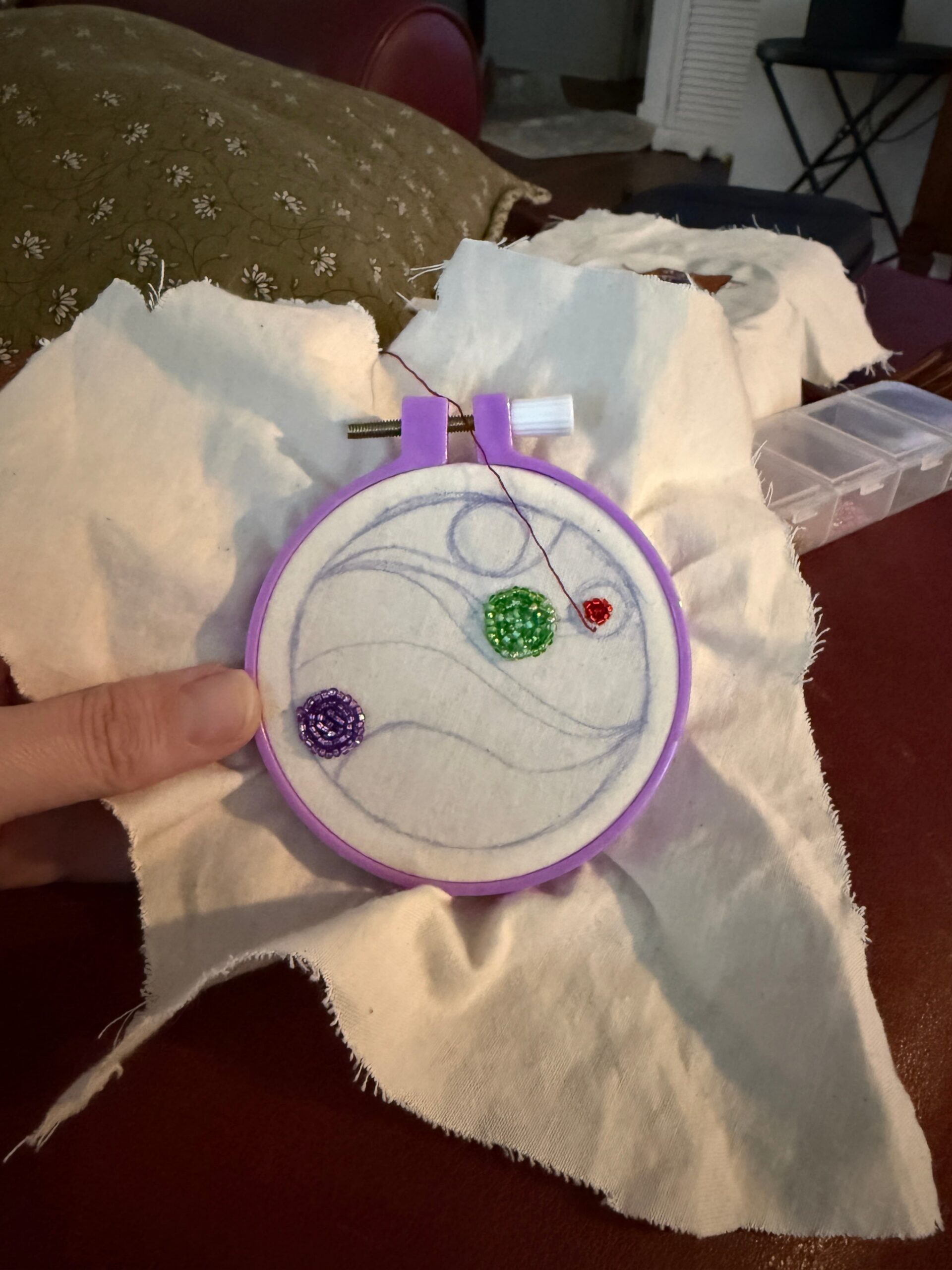 A small embroidery hoop with an abstract design sketched on it.