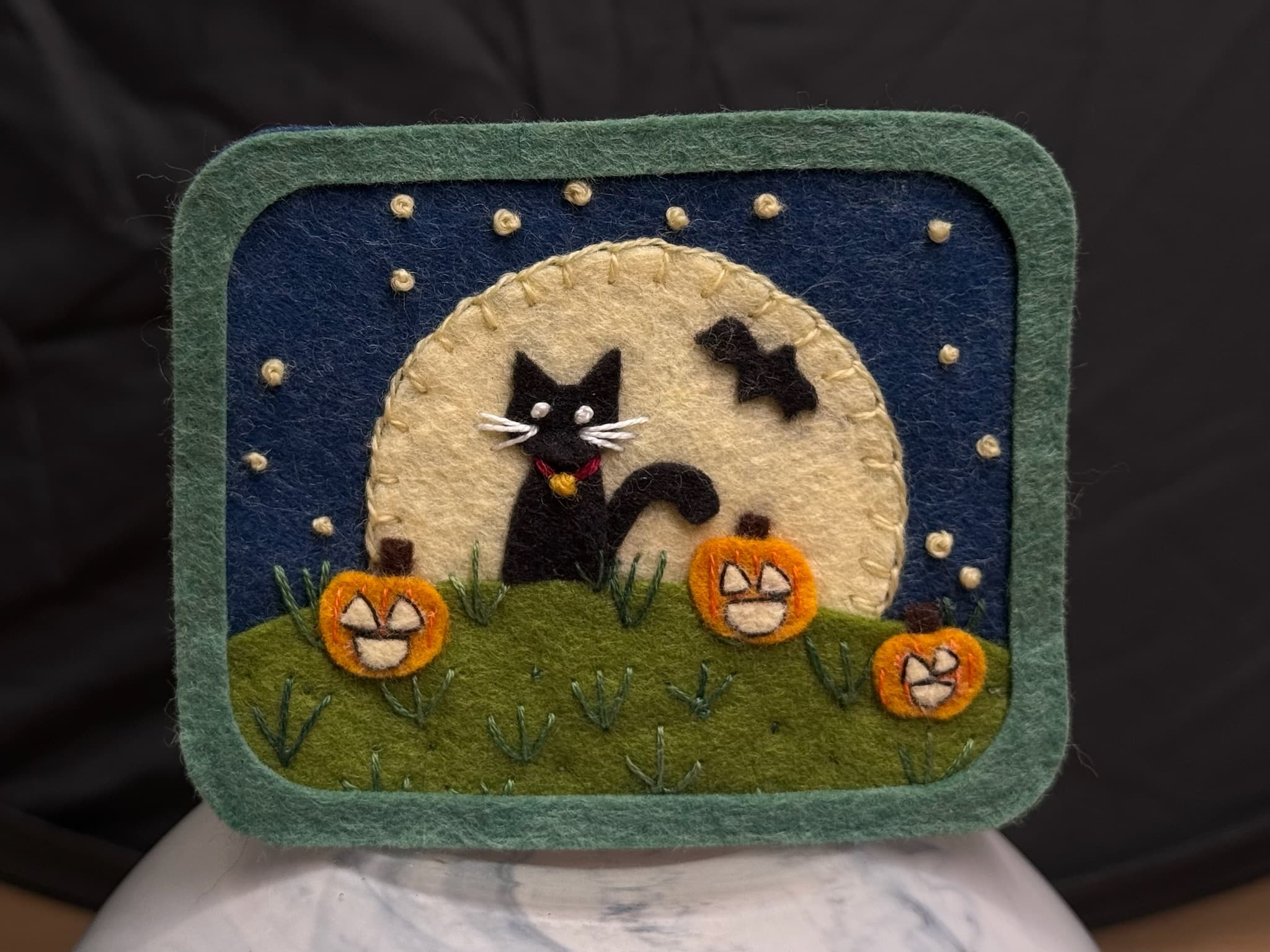 Framed felt scene of a black cat under a full moon with jack-o-lanterns and a bat