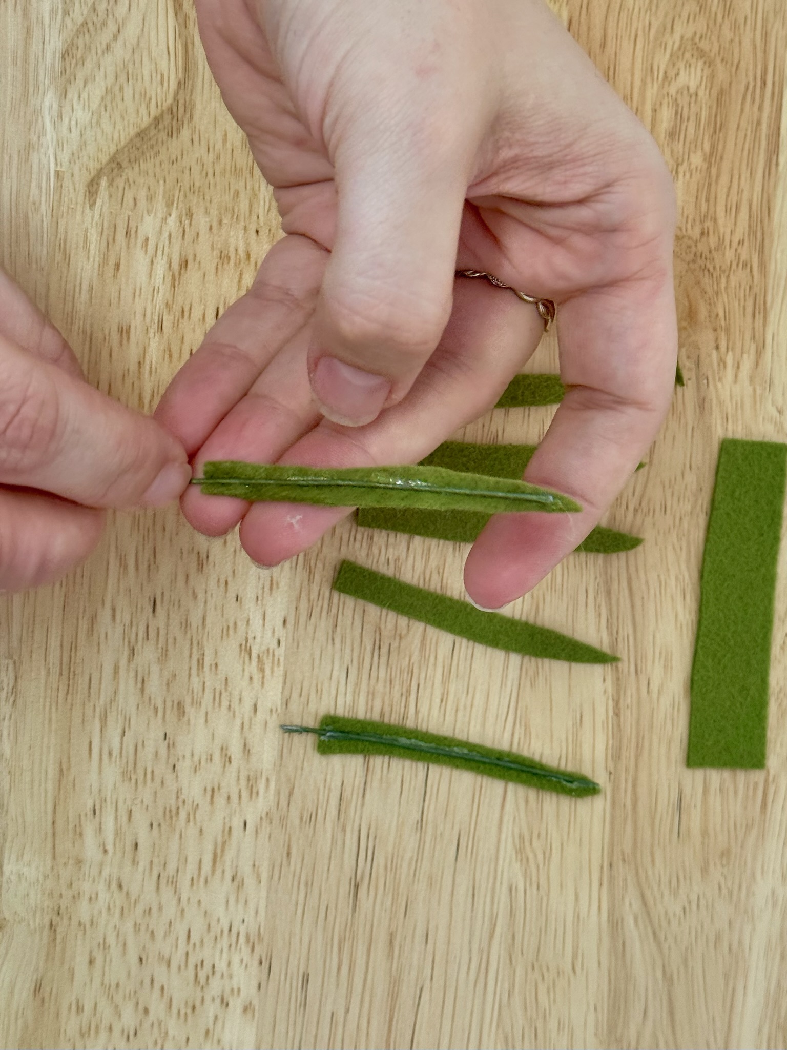 Pressing a wire into a line of glue on a green felt leaf
